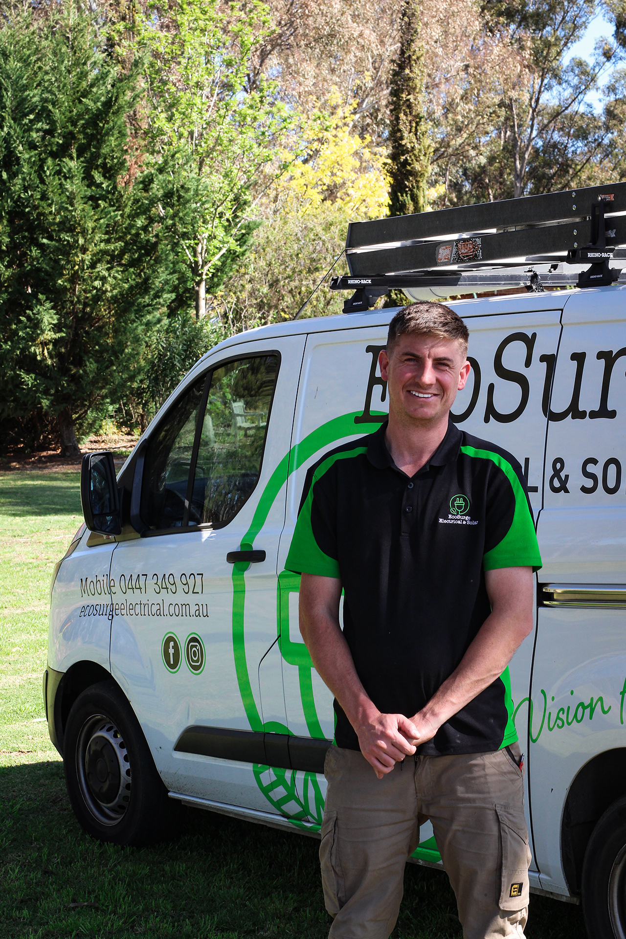 Matt from EcoSurge Electrical smiling proudly in front of a van displaying the distinctive white EcoSurge Electrical logo, showcasing professionalism and commitment to quality service in the Northern Suburbs of Adelaide.