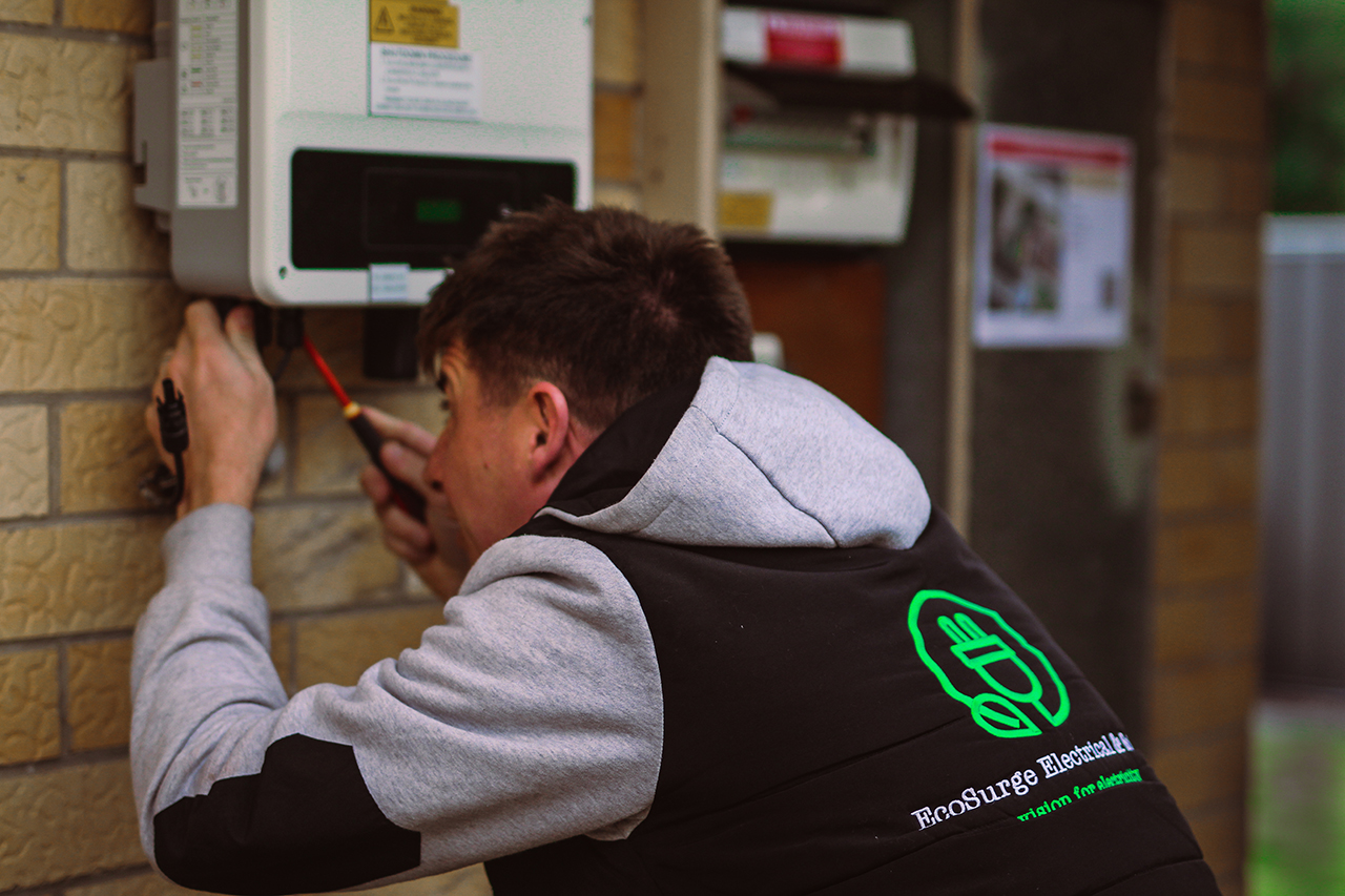 Matt from Ecosurge Electrical using screwdriver on solar inverter